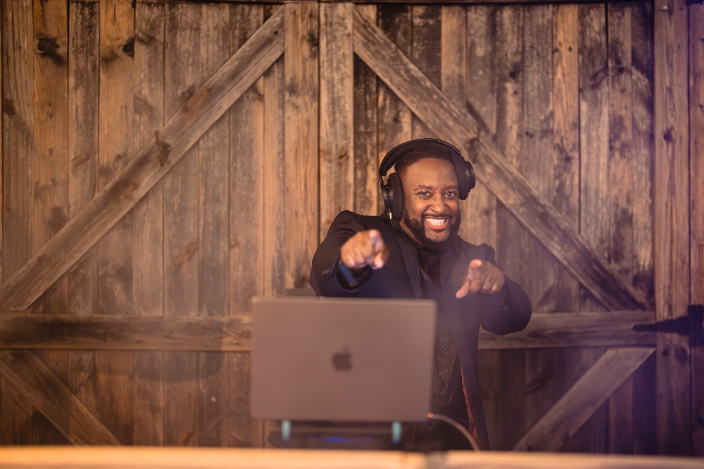 events done right tampa bay dj Cesar - How to Pick the Perfect Wedding DJ in Tampa Bay Events Done Right Tampa Bay DJ smiling and pointing at guests while mixing music on a MacBook laptop at a rustic barn wedding venue in Tampa Bay Florida